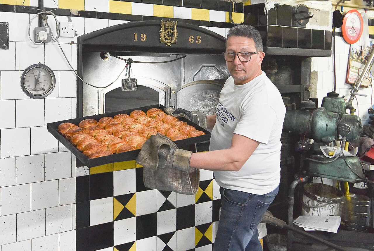 A baker with freshly baked pastizzi in Malta